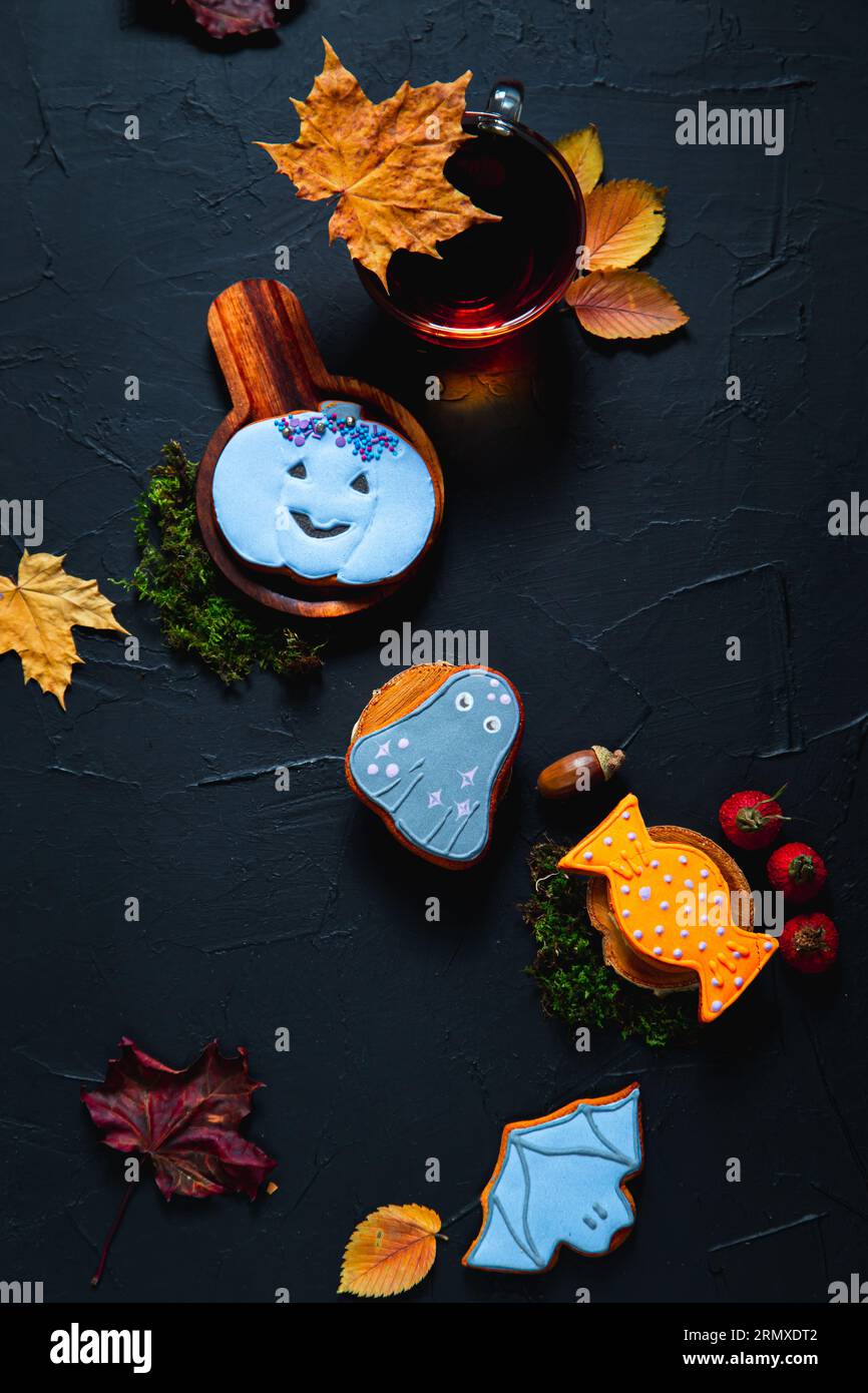 Herbsttee. Tasse Tee, bemalte Lebkuchen, Eicheln und Blätter auf schwarzem Hintergrund. Stockfoto