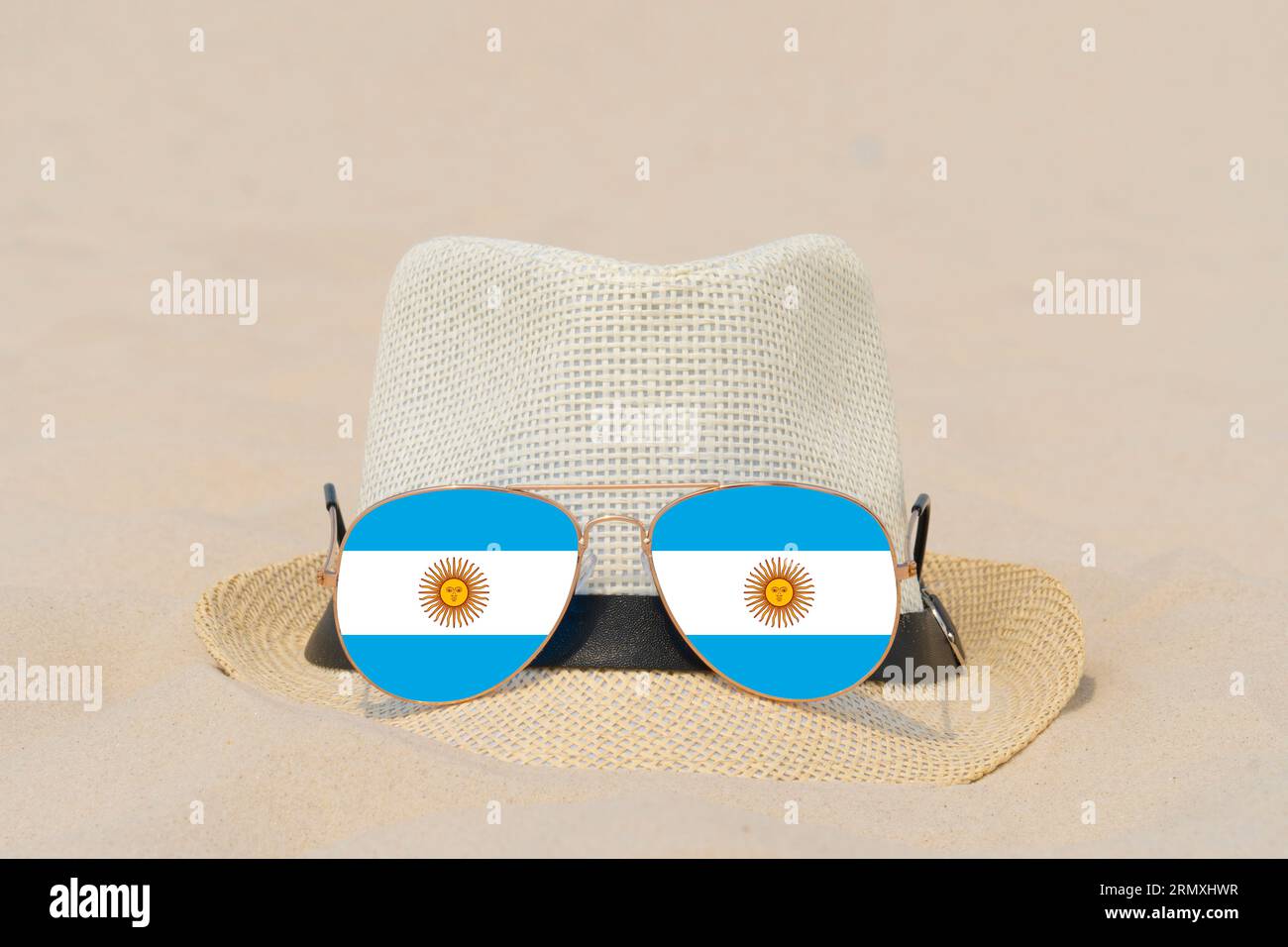 Sonnenbrille mit Brille in Form einer argentinischen Flagge und einem Hut liegen auf Sand. Konzept von Sommerferien und Reisen in Argentinien. Sommerruhe Stockfoto