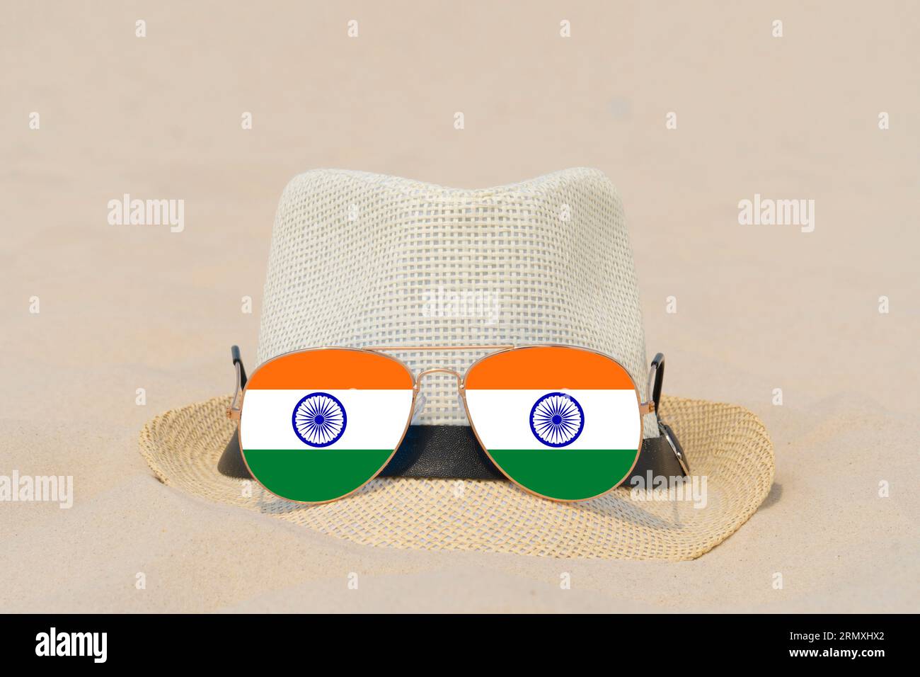 Sonnenbrille mit Brille in Form einer indischen Flagge und einem Hut liegen auf Sand. Konzept von Sommerferien und Reisen in Indien. Sommerruhe. Weihnachtszeit Stockfoto