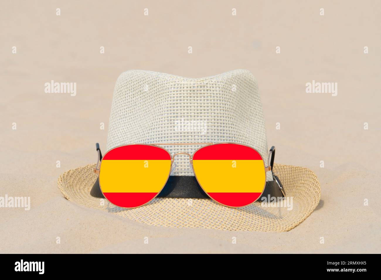 Sonnenbrille mit Brille in Form einer spanischen Flagge und einem Hut liegen auf Sand. Konzept der Sommerferien und Reisen in Spanien. Sommerruhe. Weihnachtszeit Stockfoto