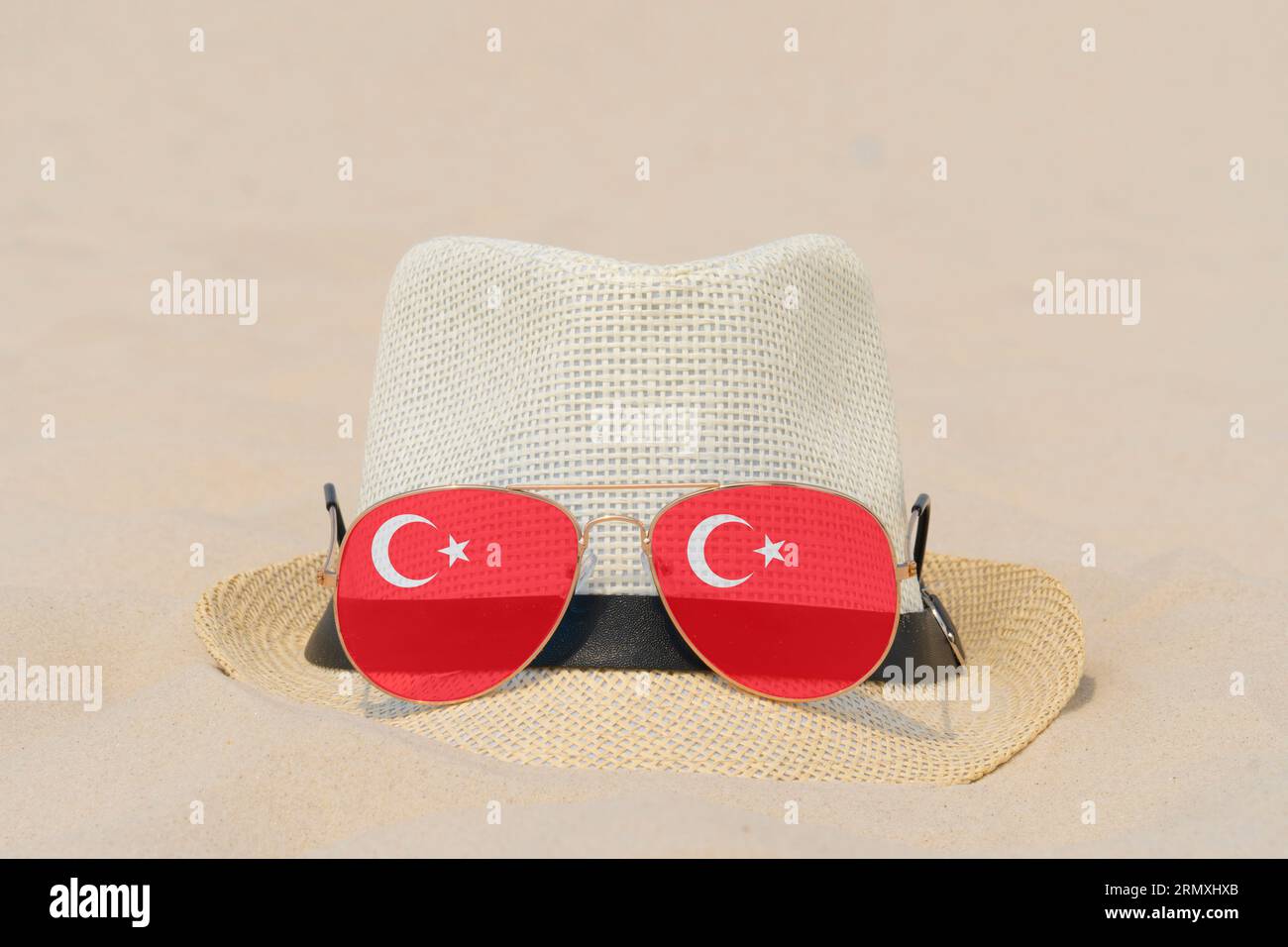 Sonnenbrille mit Gläsern in Form einer türkischen Flagge und einem Hut liegen auf Sand. Konzept von Sommerferien und Reisen in der Türkei. Sommerruhe. Weihnachtszeit Stockfoto