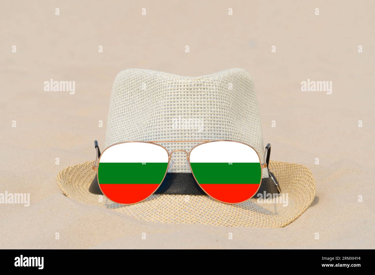 Sonnenbrillen mit Gläsern in Form einer bulgarischen Flagge und einem Hut liegen auf Sand. Konzept der Sommerferien und Reisen in Bulgarien. Sommerruhe Stockfoto