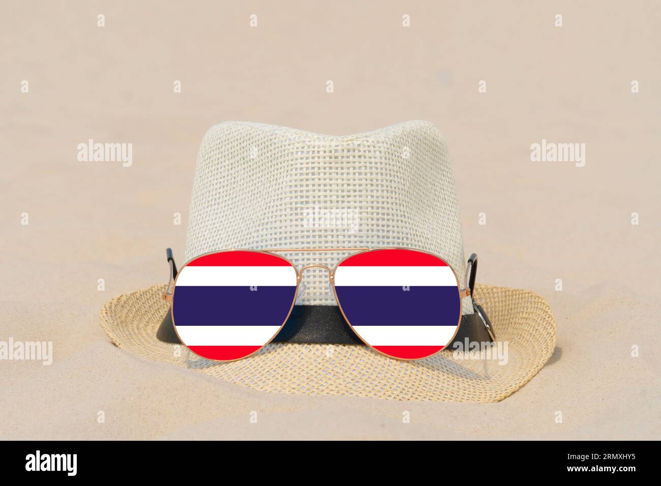Sonnenbrille mit Brille in Form einer Flagge Thailands und einem Hut liegen auf Sand. Konzept von Sommerurlaub und Reisen in Thailand. Sommerruhe Stockfoto