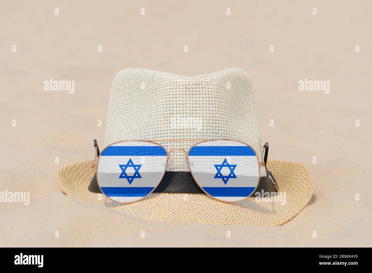 Sonnenbrille mit Gläsern in Form einer Flagge Israels und einem Hut liegen auf Sand. Konzept von Sommerferien und Reisen in Israel. Sommerruhe. Weihnachtszeit Stockfoto