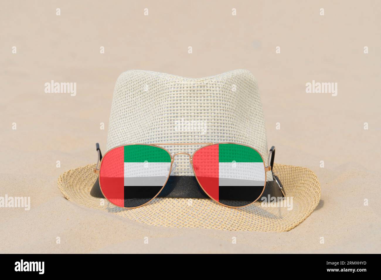 Sonnenbrille mit Brille in Form einer Flagge der Vereinigten Arabischen Emirate und einem Hut liegen auf Sand. Konzept der Sommerferien und Reisen in den Vereinigten Arabischen Emiraten Stockfoto
