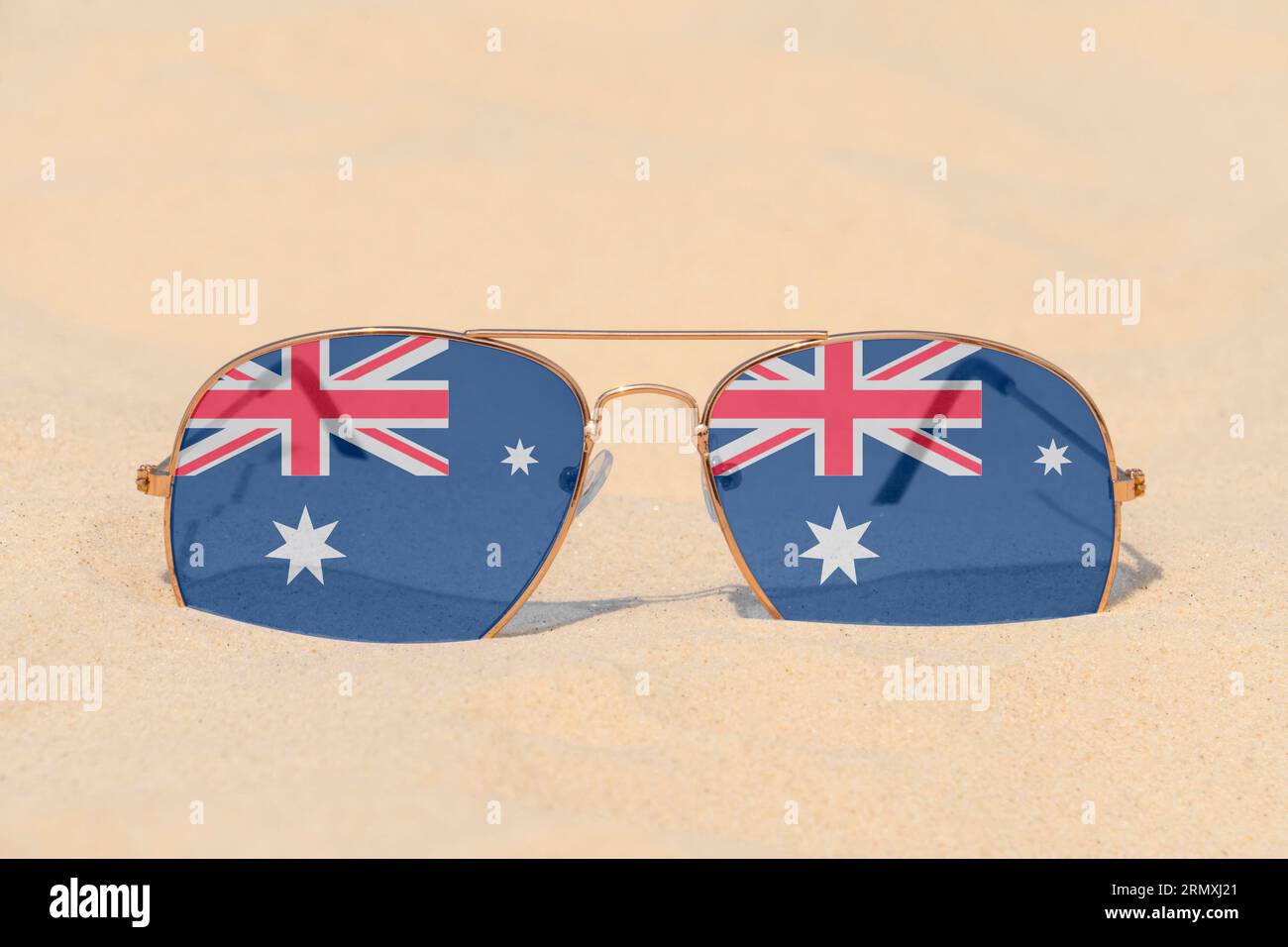 Sonnenbrillen mit Gläsern in Form einer australischen Flagge liegen auf Sand. Konzept von Sommerferien und Reisen in Australien. Sommerruhe. Weihnachtszeit Stockfoto