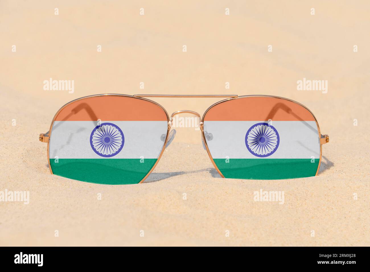 Sonnenbrillen mit Gläsern in Form einer Flagge Indiens liegen auf Sand. Konzept von Sommerferien und Reisen in Indien. Sommerruhe. Weihnachtszeit Stockfoto
