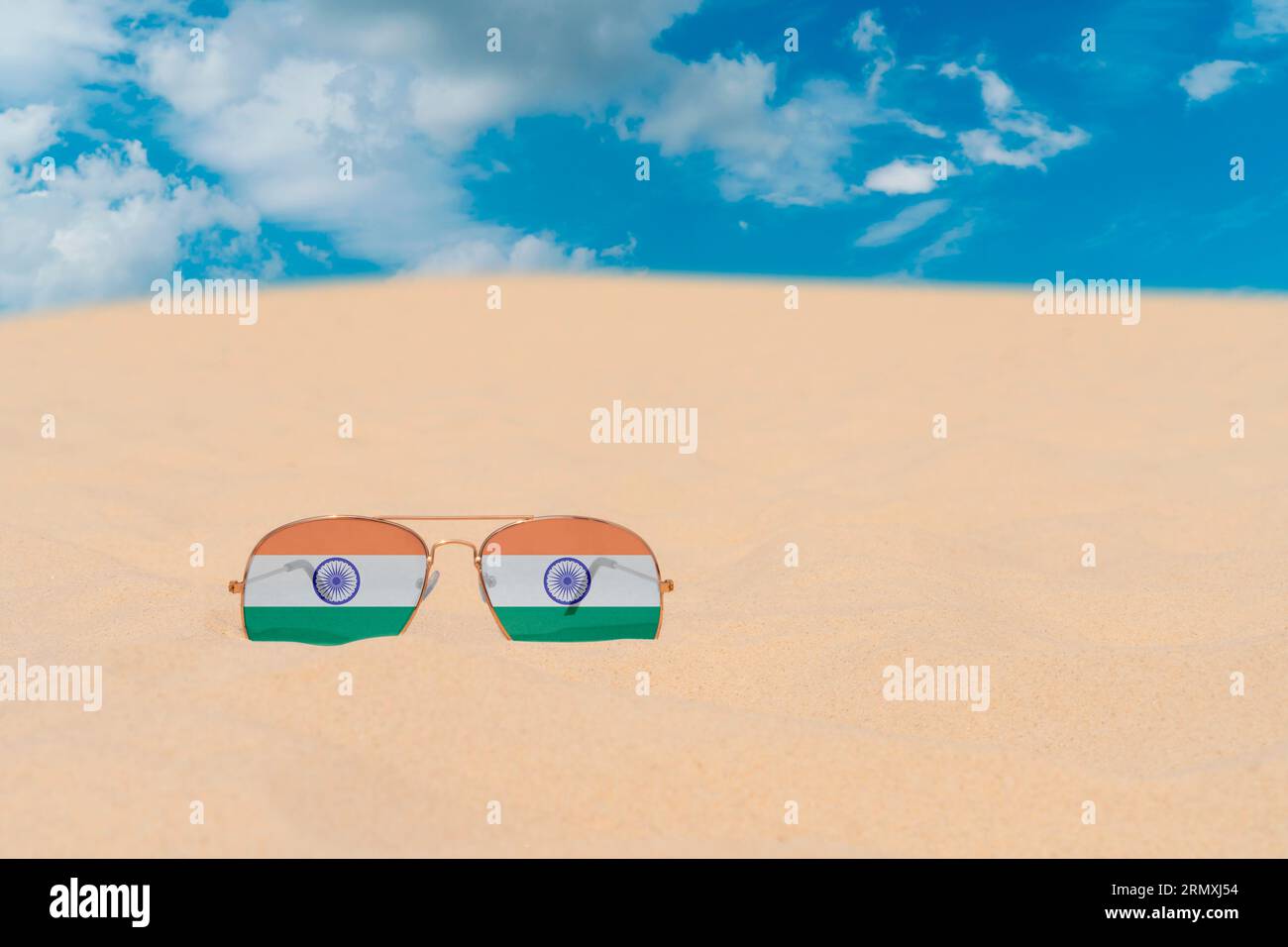 Sonnenbrillen mit Gläsern in Form einer Flagge Indiens liegen auf Sand gegen blauen Himmel. Konzept von Sommerferien, Reisen und Tourismus in Indien. Sommerruhe Stockfoto