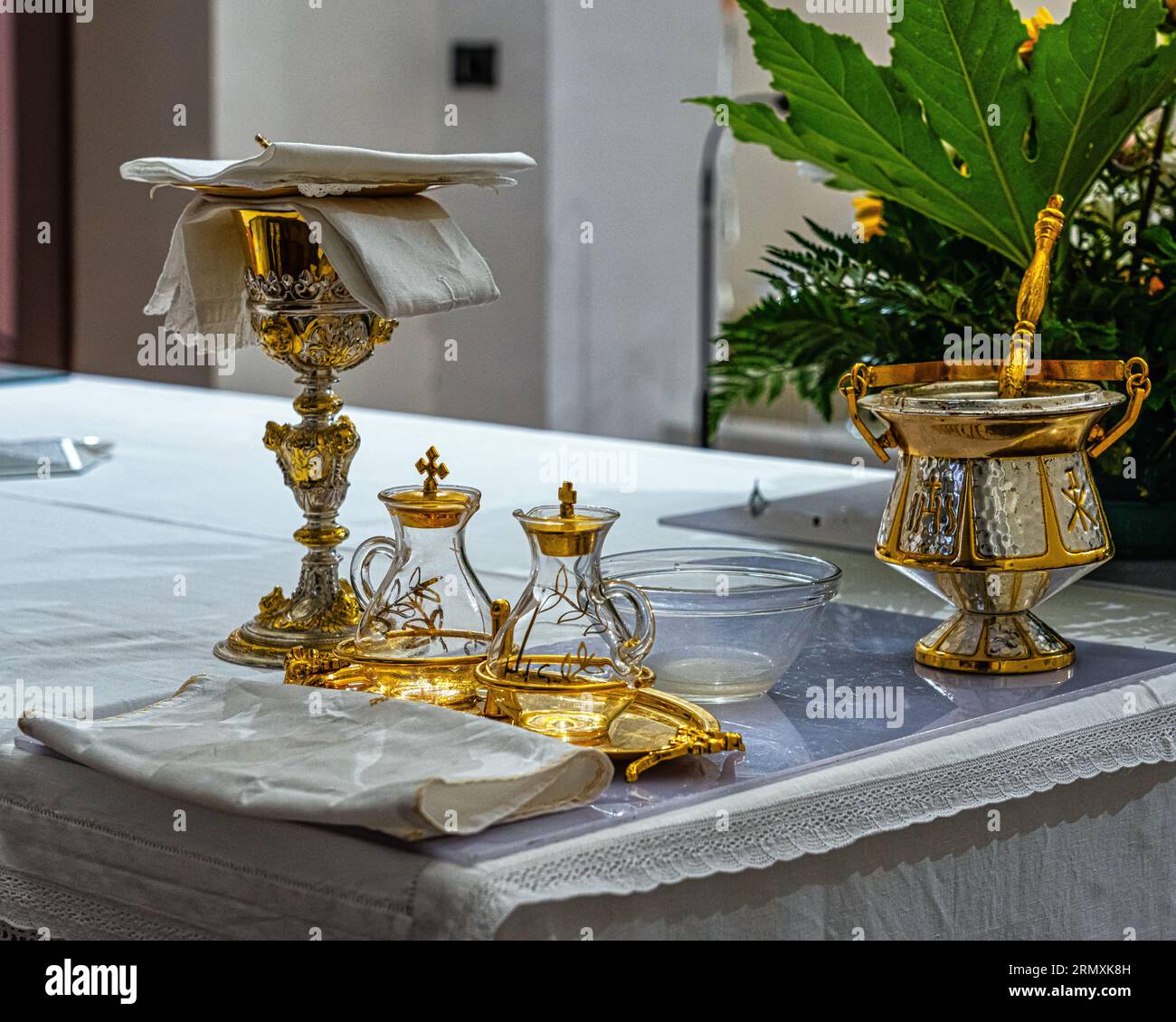 Altar mit fein verziertem Goldaspergillum, Kelch und Krusten zur Weihe des Wirtes in einer katholischen Kirche. Italien, Europa Stockfoto