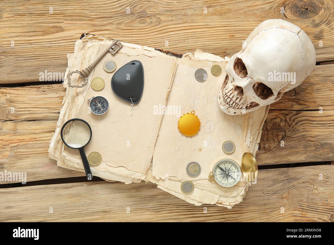 Menschlicher Schädel mit Piratenaugenfleck, alte Handschriften und Amulett auf braunem Holzgrund Stockfoto