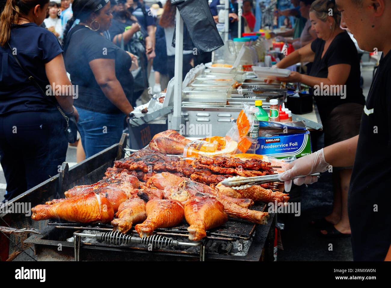 Person grillt truthahnschenkel auf einer Food Festival Street Fair am Broadway in New York City, 26. August 2023. Stockfoto
