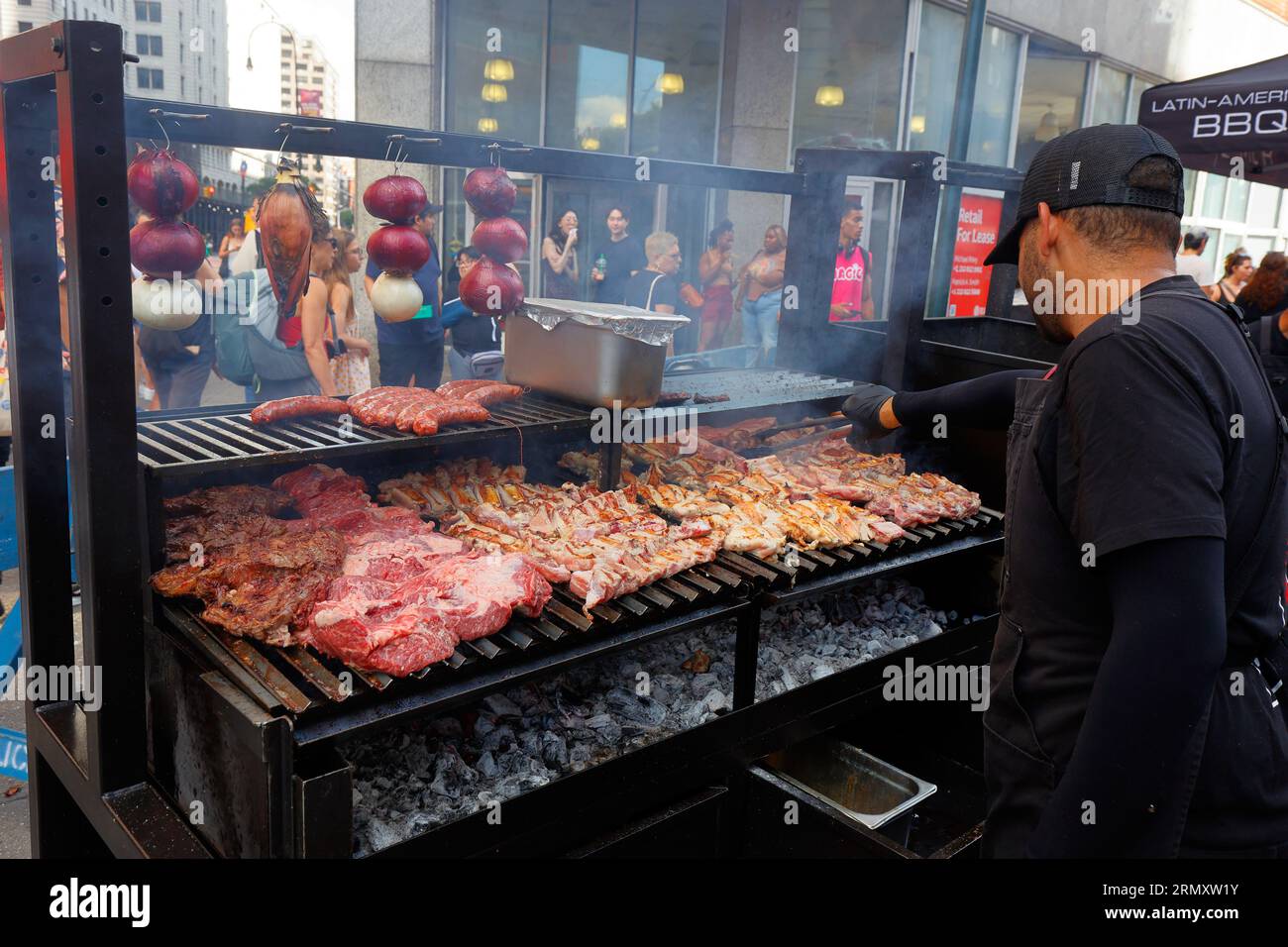 Ein lateinamerikanischer Barbecue-Mitarbeiter von Humos neigt zu einem Gaucho-Parilla-Grill auf der Philippines fest Food Festival Street Fair am 27. August 2023. Stockfoto