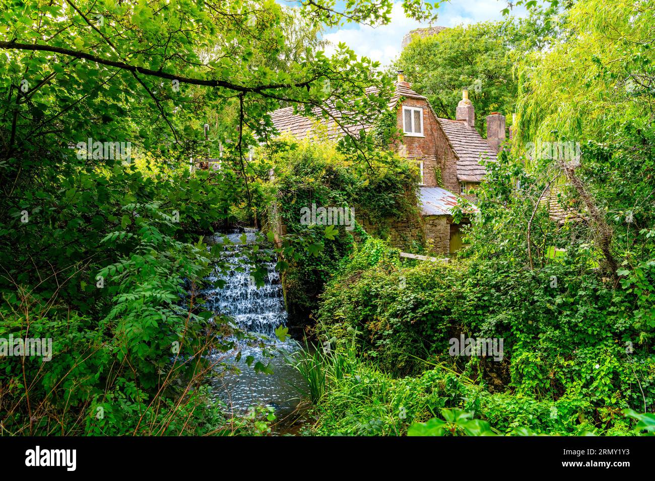 Ein malerisches Steinhaus neben einer Wassermühle und einem Wasserfall in der englischen Landschaft des Cotswold District im Südosten Englands, Großbritannien... Stockfoto