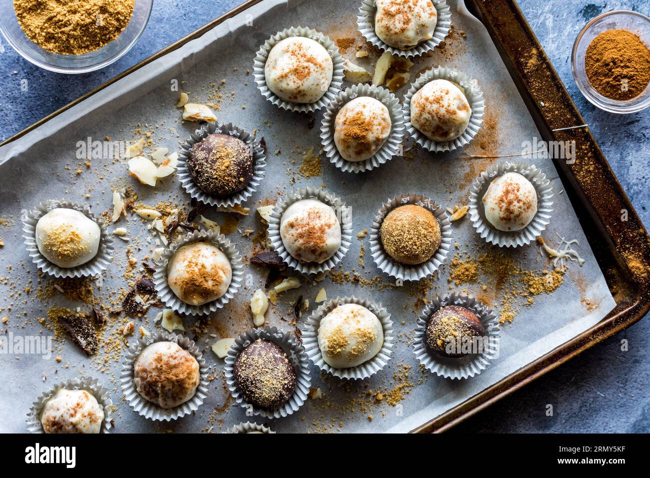 Kürbis-Gewürztrüffel in Pappbechern auf einem unordentlichen Backblech aus Pergamentpapier. Stockfoto