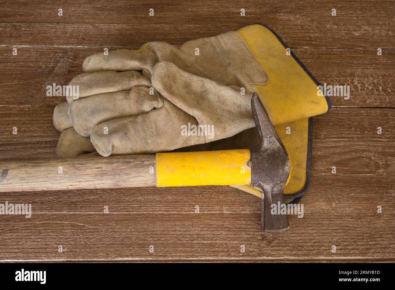 Bild eines maurerhammers und eines Arbeitshandschuhs. Verweis auf manuelle Arbeit und Sicherheit am Arbeitsplatz. Stockfoto