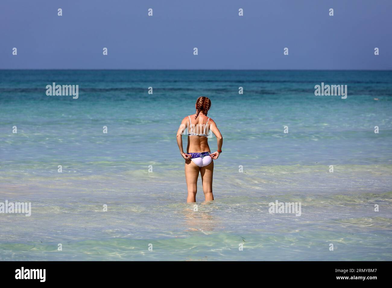 Schlankes Mädchen im Bikini, das im blauen Meerwasser schwimmt. Strandurlaub Stockfoto