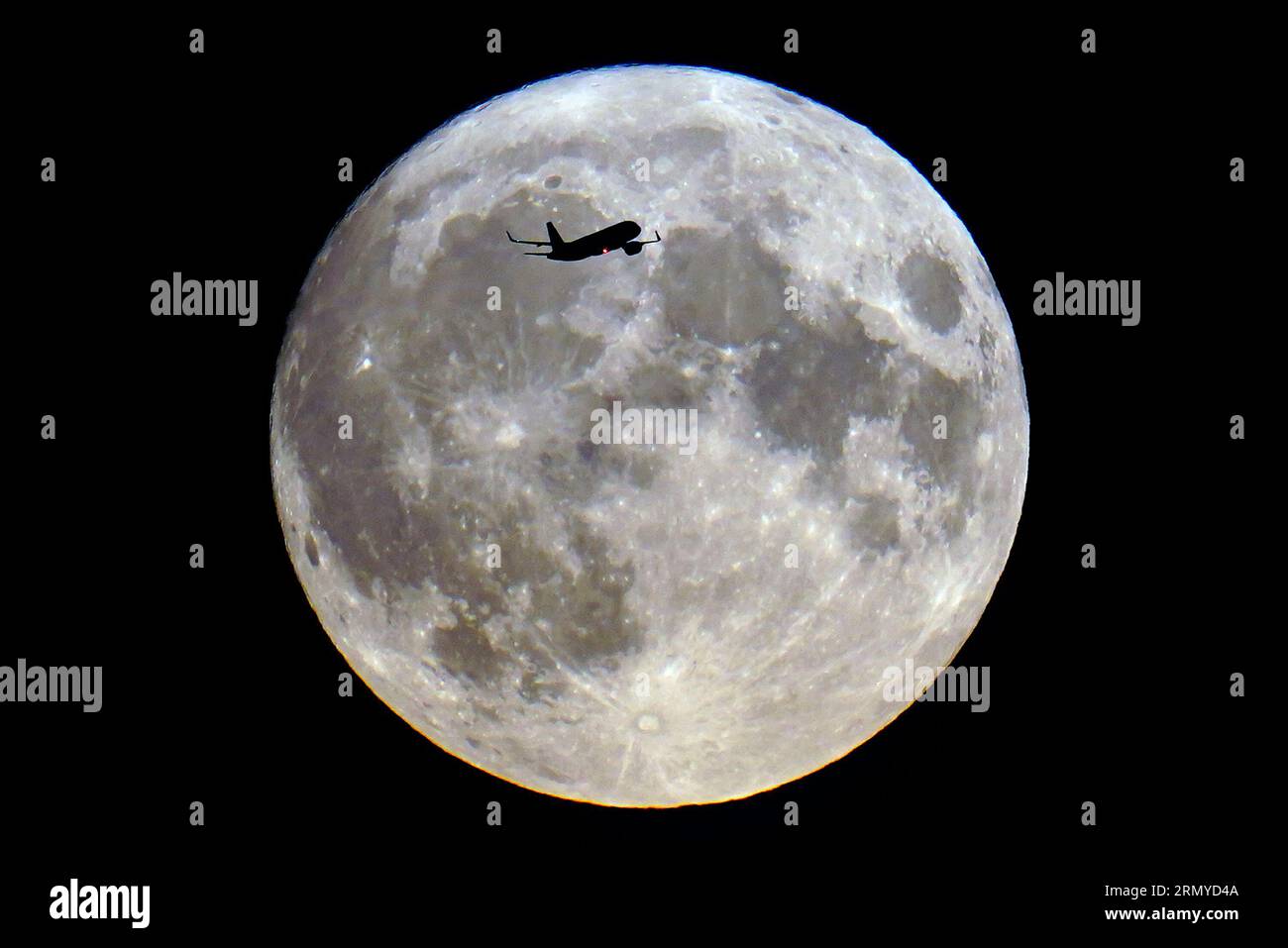 Ein Flugzeug passiert den blauen Mond in London. Der blaue Mond bezieht sich auf den zweiten Vollmond in einem Kalendermonat, der etwa alle zwei oder drei Jahre stattfindet. Dieser ist auch Supermond, wenn der natürliche Satellit der Erde etwa 14 % größer und 30 % heller am Himmel erscheint, wenn er seinen nächsten Punkt zur Erde erreicht. Bilddatum: Mittwoch, 30. August 2023. Stockfoto