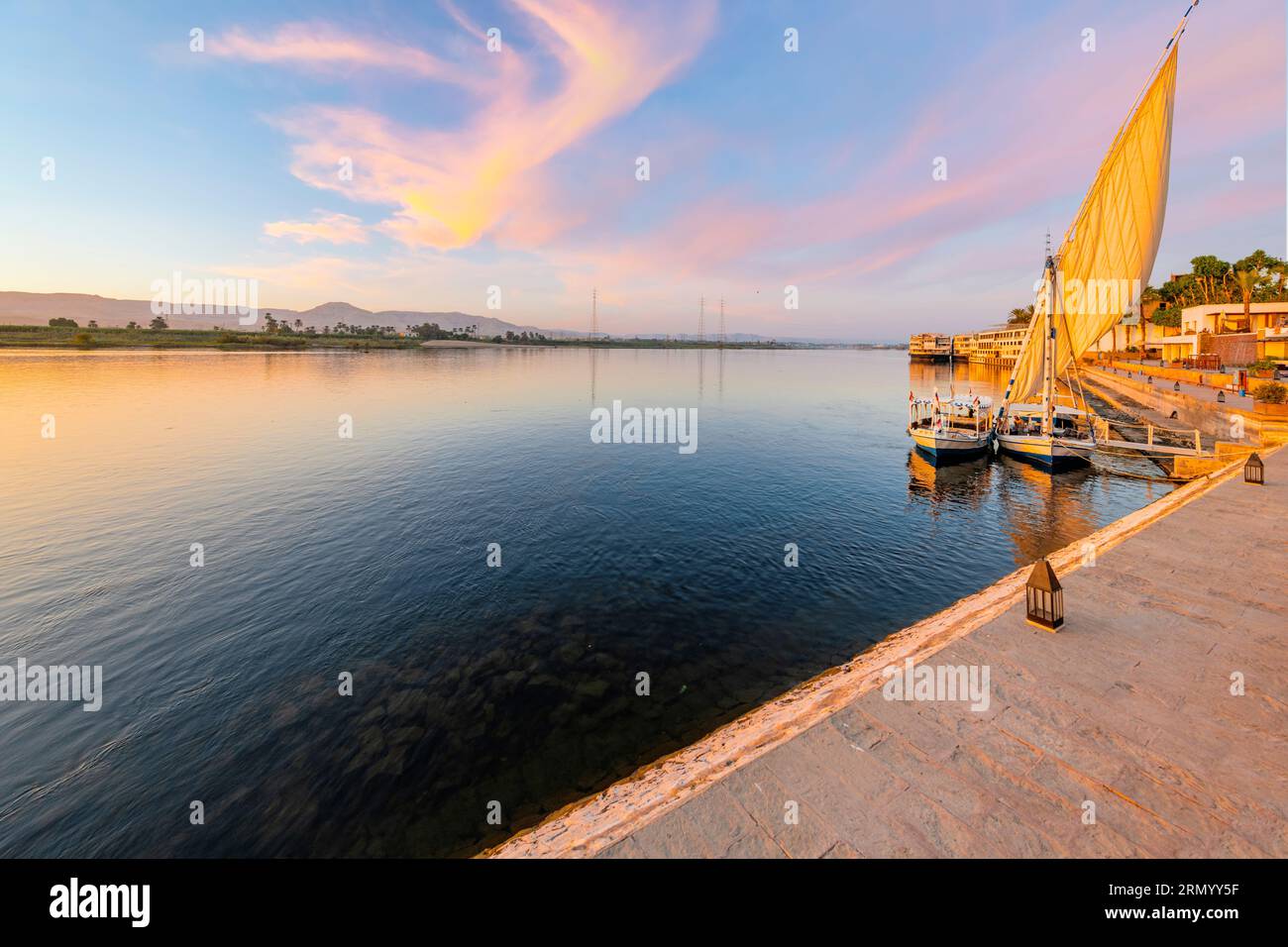Feluccas, traditionelle hölzerne Segelboote, legen bei Sonnenuntergang am Ufer des Nils in Luxor, Ägypten an. Stockfoto