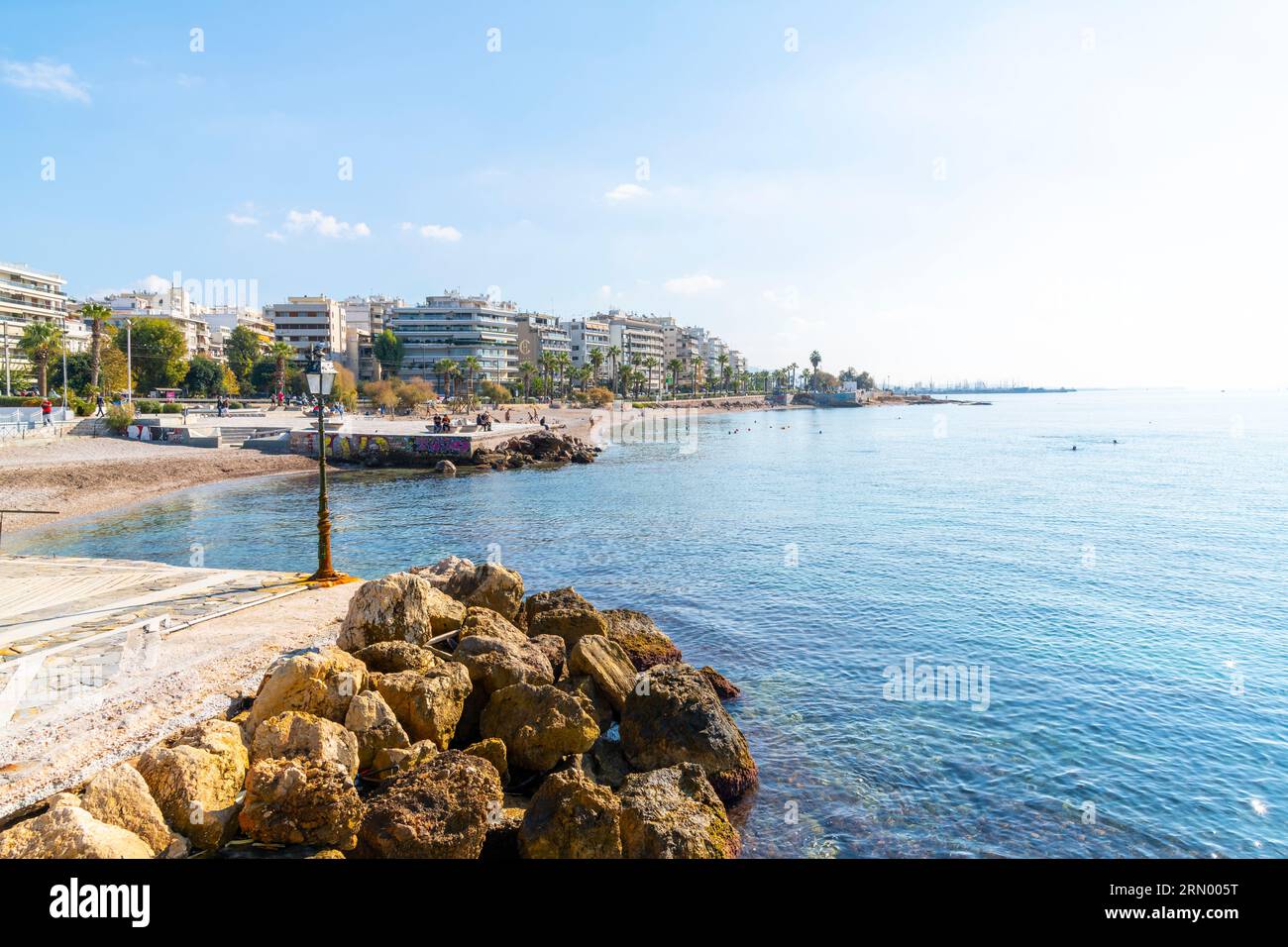 Der Strand, die Strandpromenade, der Strand und die felsige Küste von Palaio Faliro, Griechenland, mit Resort-Hotels mit Blick auf das Meer an der Athener Riviera. Stockfoto