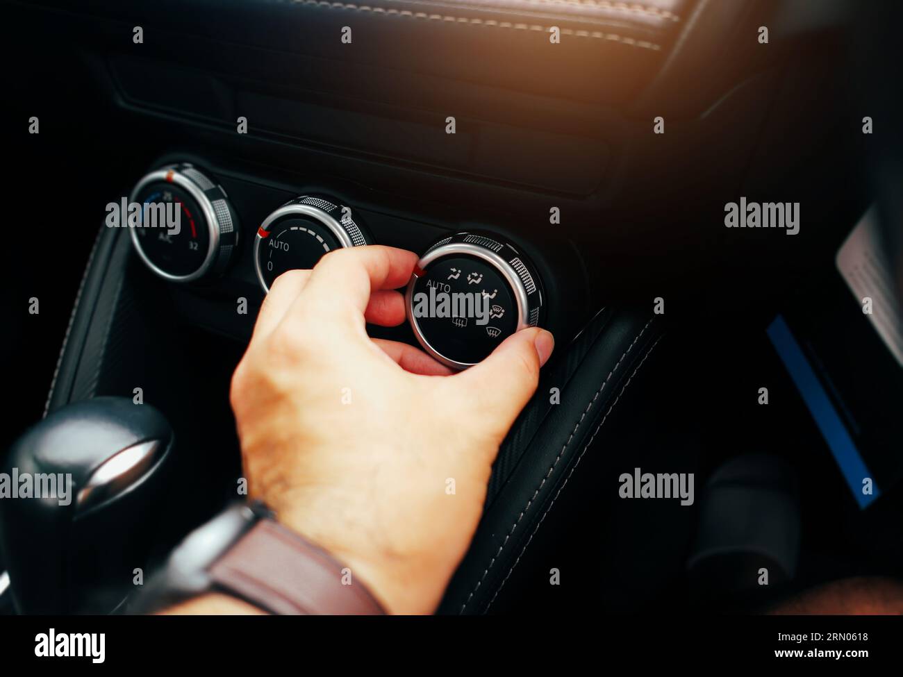 Der Fahrer stellt den Windrichtungsschalter auf dem Armaturenbrett der Klimaanlage ein. Stockfoto