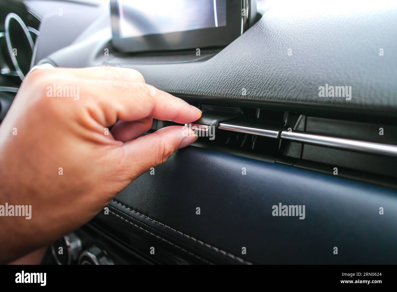 Die Fahrerhand passt die Windrichtung der Luftdüse im Fahrzeug an, die Drehrichtung der Klimaanlage im Fahrzeug wird per Knopfdruck eingestellt. Stockfoto