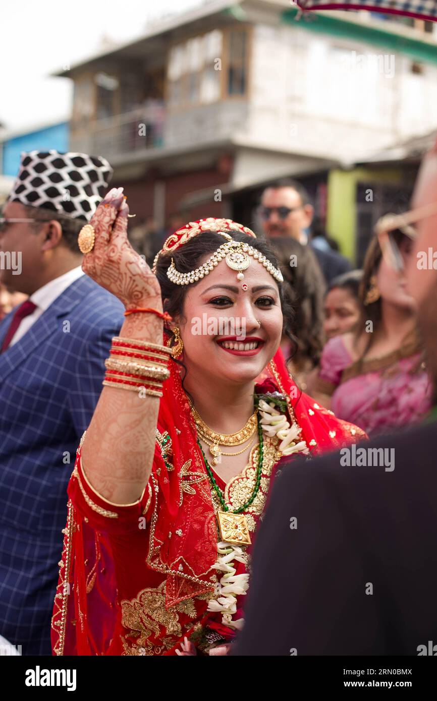 Die strahlende nepalesische Braut, in einem strahlenden roten Saris gehüllt, begrüßt ihren Bräutigam herzlich mit freudiger Vorfreude auf ihre vereinigung, ein Bild von zeitlos. Stockfoto