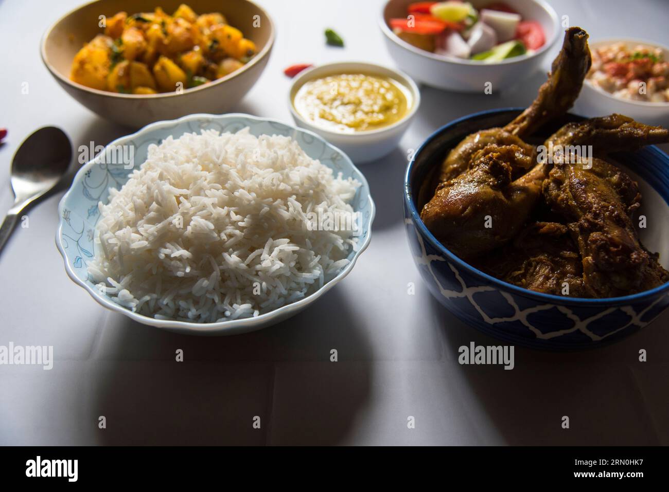 Indisches Gericht mit gedämpftem Reis und Hühnercurry, serviert mit Gewürzen. Stockfoto