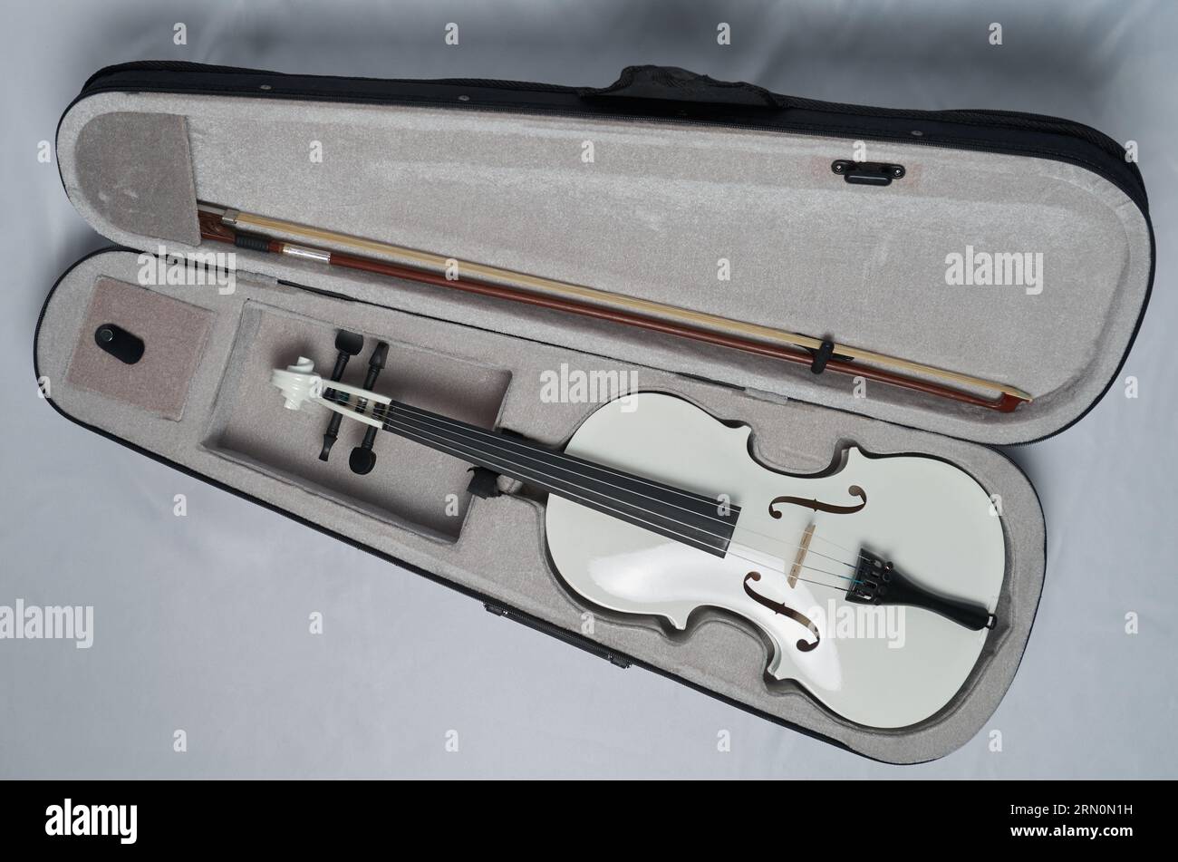 Eine weiße Violine mit Bogen liegt in einem Geigenkasten Stockfoto