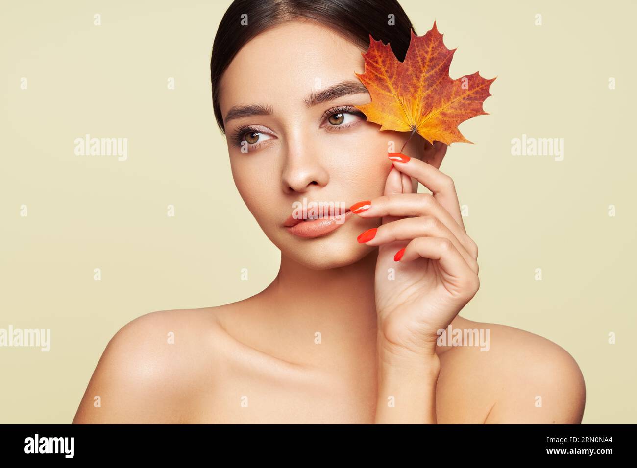 Porträt einer schönen jungen Frau mit Herbstblättern. Gesunde saubere frische Haut natürliche Make-up Beauty-Augen und rote Nägel Stockfoto