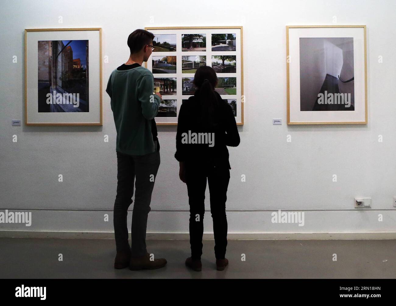 Besucher bewundern Fotos von Matthias Matzak während der Eröffnungszeremonie der Ausstellung LICHT LUFT SONNE: Das neue Frankfurt im Deutschen Architekturmuseum in Frankfurt, Deutschland, am 05. Dezember 2014. Zwischen 1925 und 1930 verwandelte sich die Stadt Frankfurt in einen Hotspot der Avantgarde-Neubaubewegung, die den gesamten europäischen Kontinent in ihren Bann zog. Im Mittelpunkt dieser Entwicklung stand das Bestreben, Sozialwohnungen zu bauen. 2008 begann der Frankfurter Fotokünstler Matthias Matzak, die Überreste dieses Vermächtnisses mit seiner Kamera aufzunehmen. Er entschied sich für einen subjektiven Ansatz der Architektur und malte so A Stockfoto