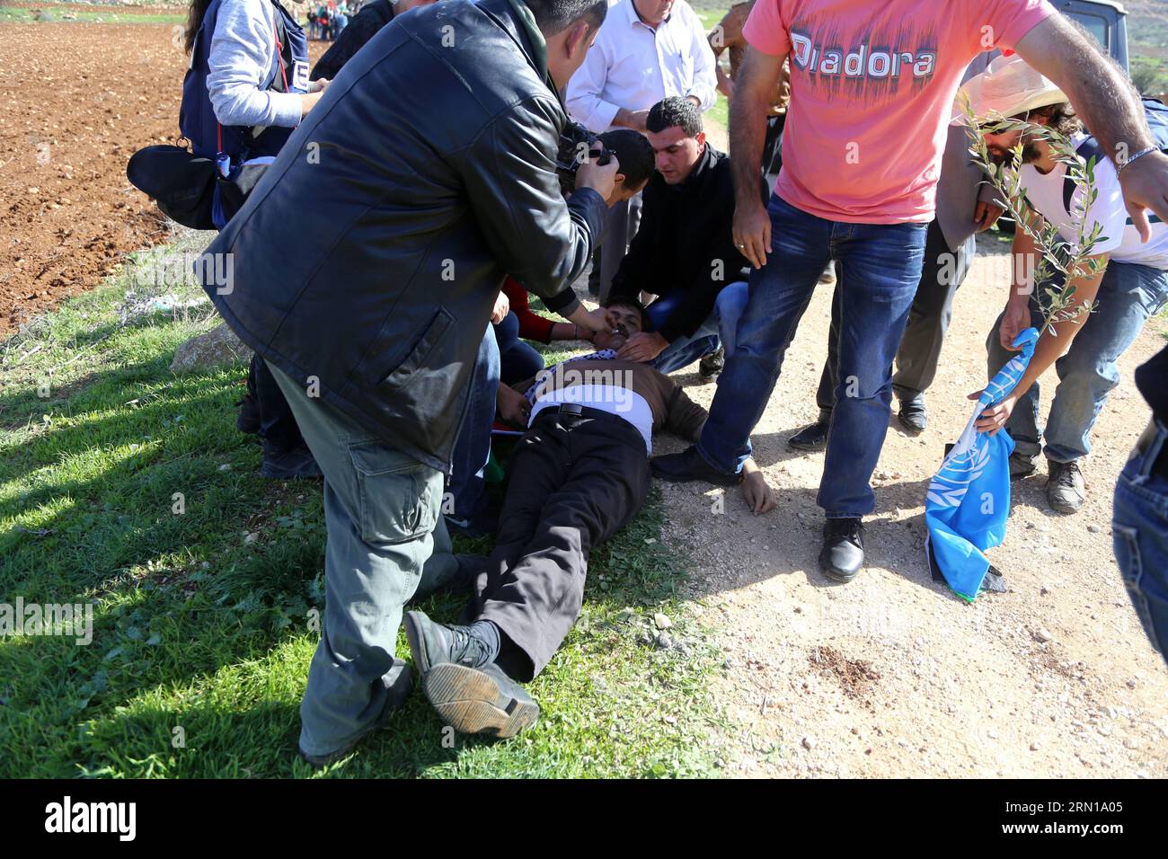 POLITIK Palästinensischer Minister kommt bei Konflikt mit israelischen Soldaten um (141210) -- RAMALLAH, 10. Dezember 2014 -- Demonstranten versuchen, den palästinensischen Beamten Ziad Abu ein (C), der für die Frage israelischer Siedlungen für die Palästinensische Autonomiebehörde verantwortlich ist, zu behandeln, nachdem er bei einem Protest im Dorf Turmus Aya in der Nähe von Ramallah am 10. Dezember 2014 verletzt wurde. Der palästinensische Beamte starb am Mittwoch, nachdem ihn israelische Soldaten bei Zusammenstößen zwischen israelischen Streitkräften und palästinensischen Demonstranten angegriffen hatten, sagten offizielle palästinensische Quellen. (LMZ) MIDEAST-RAMALLAH-PALESTINIAN-OFFIC Stockfoto