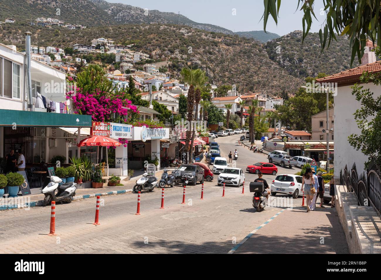 Belebte Straße in der Altstadt von Kalkan mit Villen am Hang im Hintergrund, Kalkan, Türkei Stockfoto
