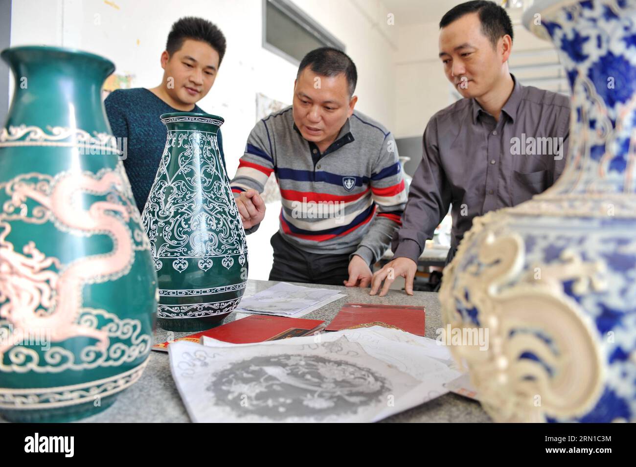Die Lackfaden-Bildhauer Zhang Jiansheng (C) und Wang Guozhi (R) diskutieren am 16. Dezember 2014 in einem Studio in Xiamen, südöstlich der Provinz Fujian. Lackfäden-Modellierung ist eine Kunst im Südosten Chinas, die gut temperierte Lackfäden verwendet, um dekorative Muster zu erstellen. Die Mitte des 17. Jahrhunderts entstandene Lackgarnskulptur ist als eines der nationalen immateriellen Erben Chinas aufgeführt. ) (lmm) CHINA-FUJIAN-XIAMEN-ART-LACK FADENBILDHAUEREI (CN) LinxShanchuan PUBLICATIONxNOTxINxCHN Lack FADEN Zhang Jiansheng C und Wang r diskutieren einige Arbeiten IN einem Studio Stockfoto