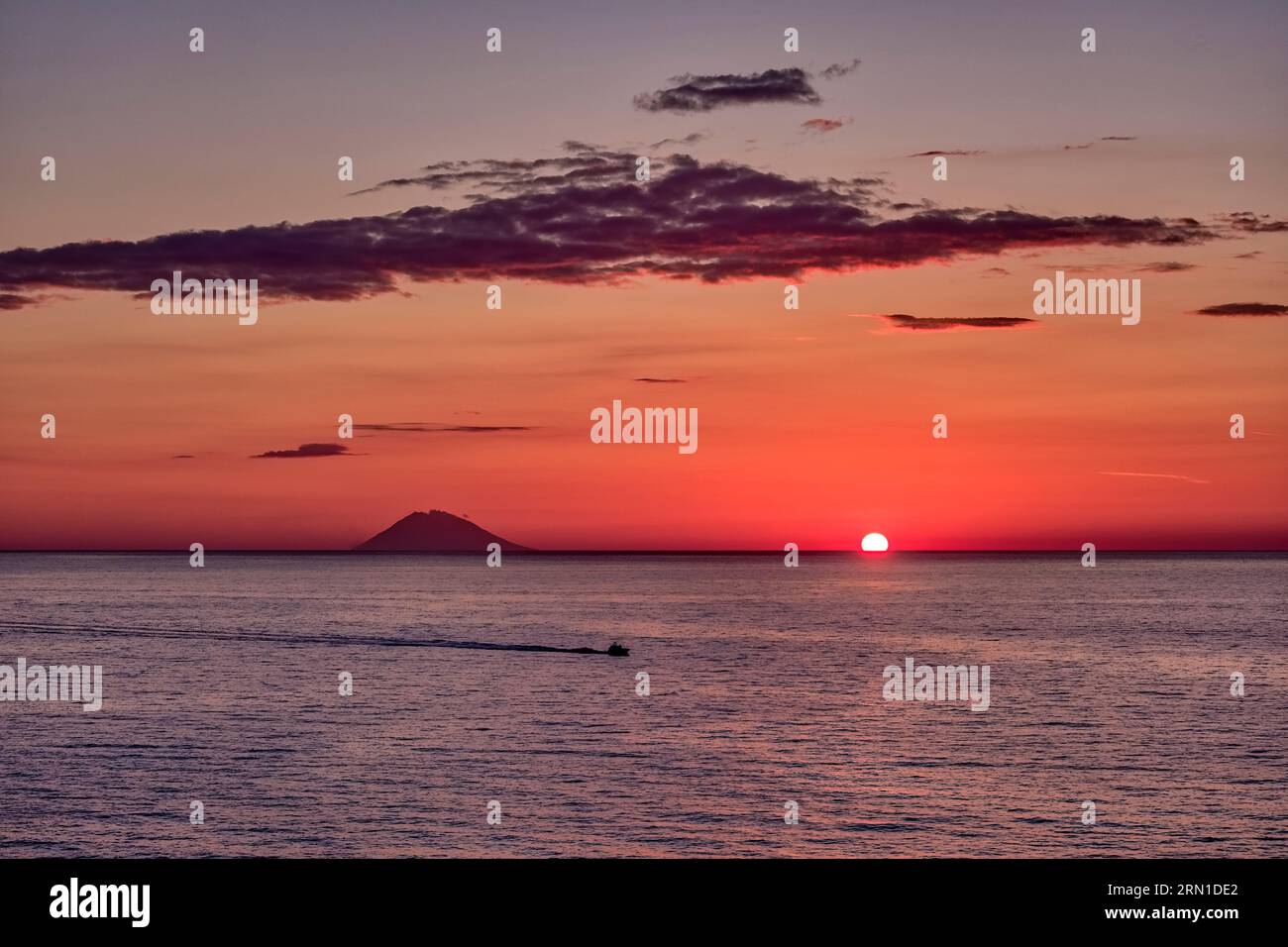 Die Sonne untergeht über dem Wasser in der Nähe der Vulkaninsel Stromboli, von Tropea aus gesehen. Stockfoto