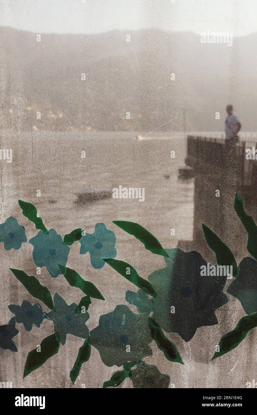 Mann, der vor dem Comer See hinter einem Vorhang mit Blumenmuster steht Stockfoto