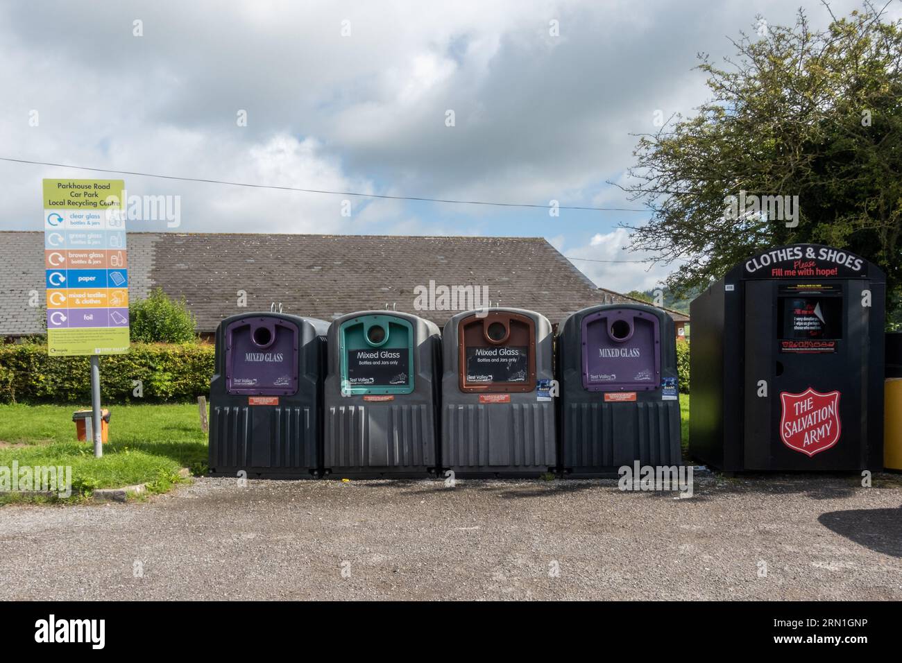 Lokale Recyclingstelle in einem Dorfparkplatz mit Abfalleimern für verschiedene Glasfarben und einem Abfalleimer der Heilsarmee für Textilschuhe, England, Großbritannien Stockfoto