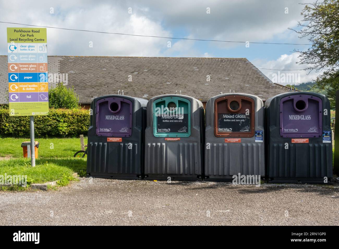 Lokale Recyclingstelle in einem Dorfparkplatz mit Behältern für verschiedene Glasfarben, England, Großbritannien Stockfoto