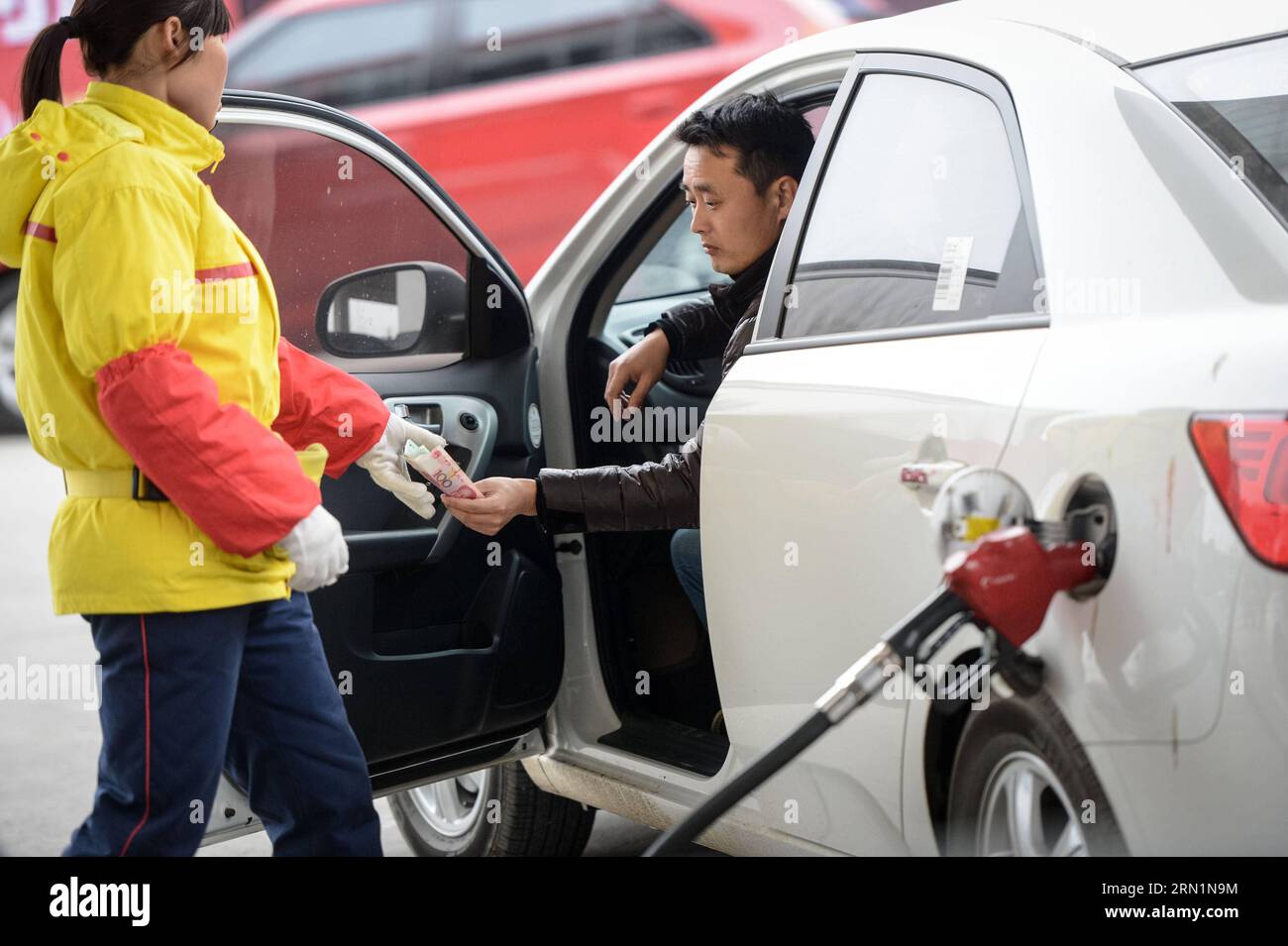 (150112) -- HEFEI, 12. Januar 2015 -- Ein Fahrer bezahlt den Treibstoff an einer Tankstelle in Hefei, Hauptstadt der ostchinesischen Provinz Anhui, 12. Januar 2015. Chinas bester Wirtschaftsplaner, die nationale Entwicklungs- und Reformkommission, gab am Montag eine Senkung des Verkaufspreises für Benzin um 180 Yuan (29 US-Dollar) und für Diesel um 230 Yuan (37 US-Dollar) pro Tonne bekannt. In der Zwischenzeit wird die Steuer auf Benzin von 1,4 Yuan auf 1,52 Yuan pro Liter steigen. Die Abgabe auf Diesel wird nach Angaben des Finanzministeriums und der staatlichen Steuerverwaltung von 1,1 Yuan pro Liter auf 1,2 Yuan erhöht. ) Stockfoto