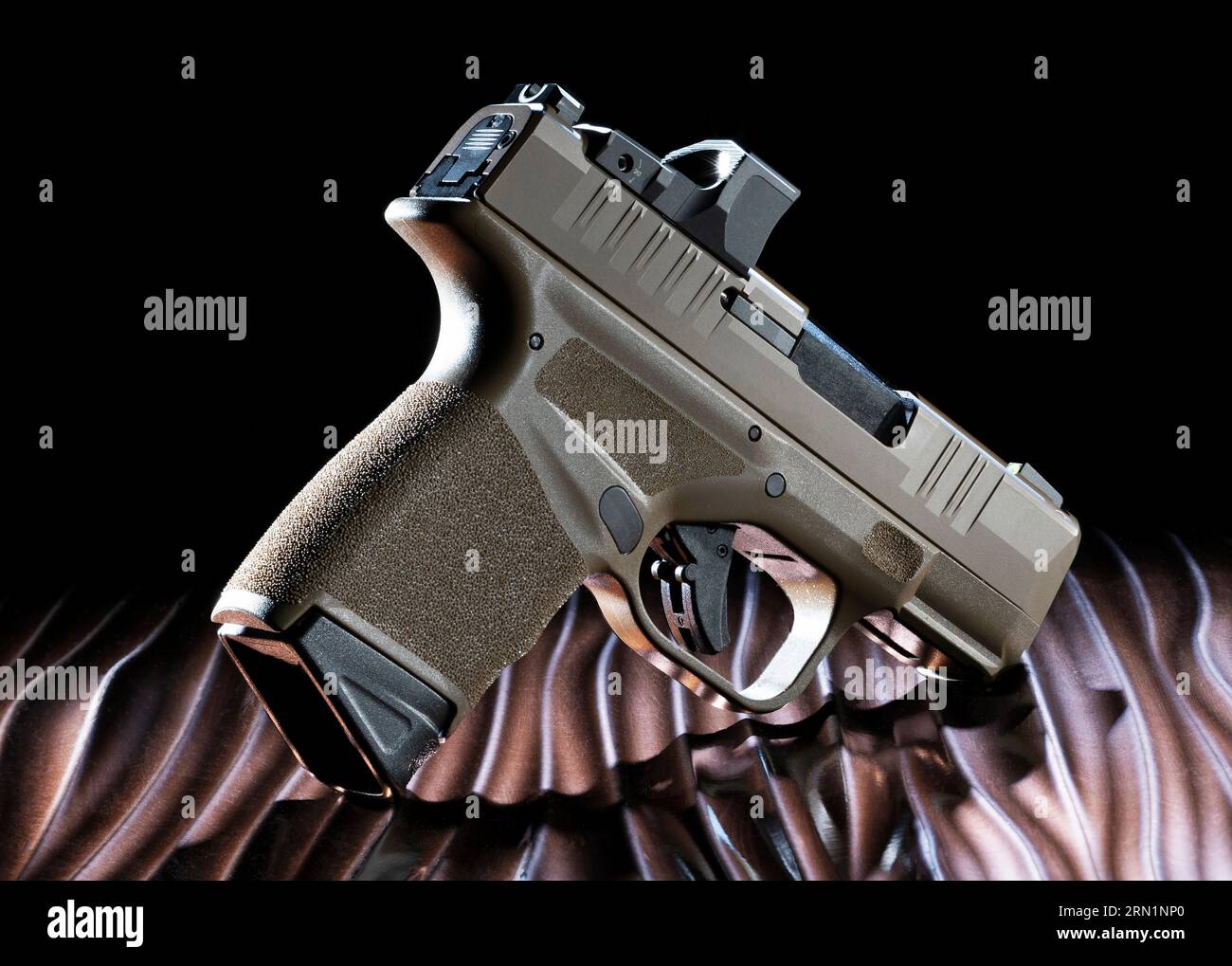 Halbautomatische 8-mm-Pistole auf einem gewellten bronzefarbenen Tisch mit dunklem Hintergrund Stockfoto