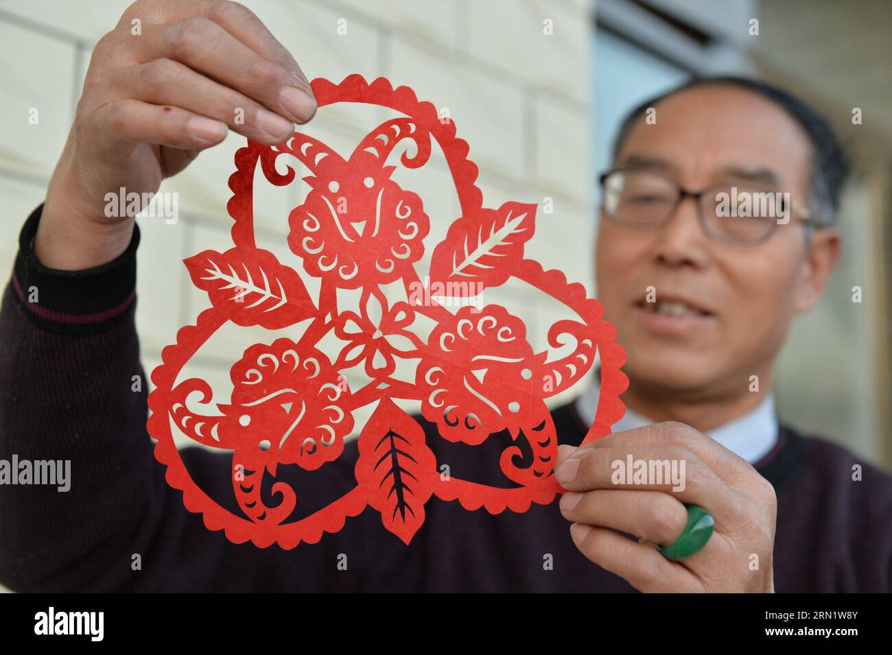HEJIAN, 21. Januar 2015 -- der Volkskünstler Song Baoshu zeigt eine Papierschnitzerei von Schafen in der Stadt Hejian, nordchinesische Provinz Hebei, 21. Januar 2015. Mit einer Schere und etwas Papier können chinesische Handwerker Papierschnitte mit komplexen Designs und Bildern erstellen. Als das Papercutting im Blut läuft, widmet sich der 61-jährige Song Baoshu der Erhaltung des Papercutts. (wh) CHINA-HEBEI PROVINCE-HEJIAN-PAPERCUTTINGS(CN) ZhuxXudong PUBLICATIONxNOTxINxCHN Hejian Jan 21 2015 Folk Artist Song Baoshu zeigt in Hejian City North China S Hebei Province Jan 21 2015 mit einer Schere ein Papierschneiden von Scheren Stockfoto