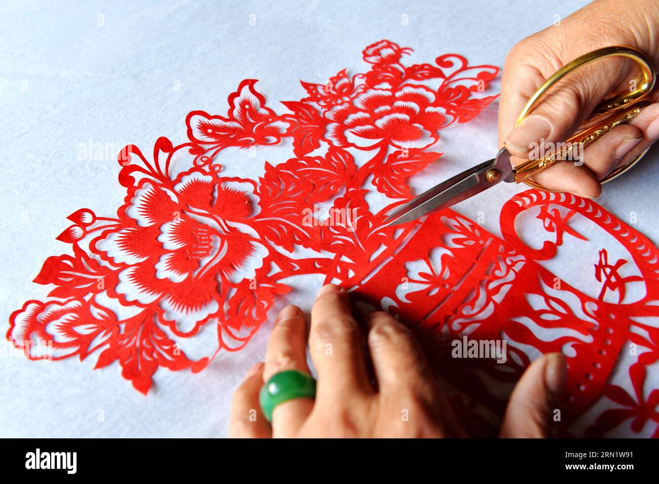 HEJIAN, 21. Januar 2015 -- der Volkskünstler Song Baoshu macht eine Taschenschrift in Hejian City, nordchinesische Provinz Hebei, 21. Januar 2015. Mit einer Schere und etwas Papier können chinesische Handwerker Papierschnitte mit komplexen Designs und Bildern erstellen. Als das Papercutting im Blut läuft, widmet sich der 61-jährige Song Baoshu der Erhaltung des Papercutts. (wh) CHINA-HEBEI PROVINCE-HEJIAN-PAPERCUTTINGS(CN) ZhuxXudong PUBLICATIONxNOTxINxCHN Hejian Jan 21 2015 Volkskünstler Song Baoshu schneidet in Hejian City Nordchina S Hebei Province 21 2015 mit einer Schere und etwas Papier Chi Stockfoto