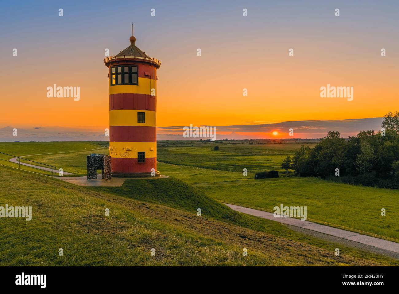 Ein Bild eines Sonnenaufgangs am Leuchtturm von Pilsum, der sich zwischen Pilsum und Greetsiel am Nordseedeich befindet, der zur Gemeinde Krum gehört Stockfoto