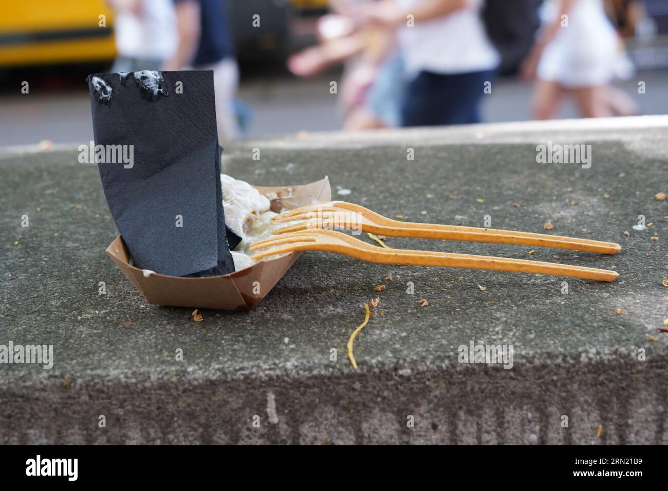 Einweggabeln mit gebrauchten Servietten an einem Papierbehälter für Straßennahrung anlehnen. Stockfoto