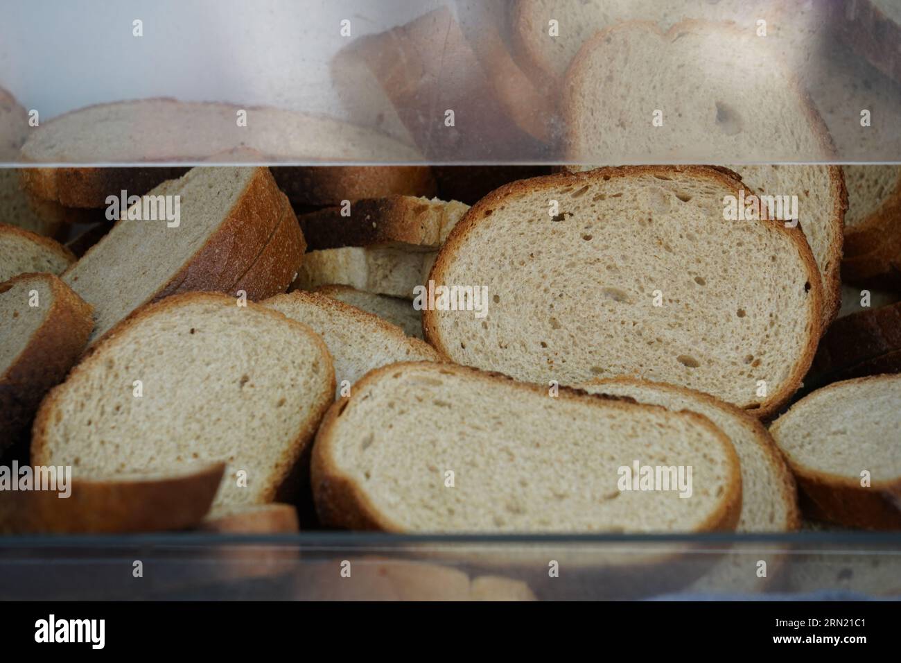 Brotscheiben in einem durchsichtigen Kunststoffbehälter mit einer Öffnung zum Herausnehmen. Stockfoto