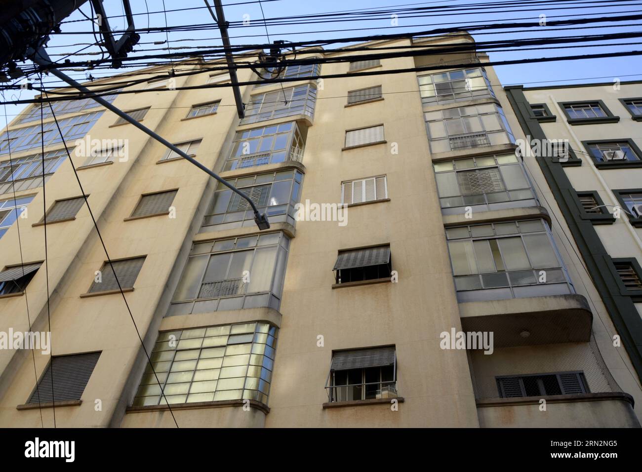 Fassade eines alten Gebäudes mit Blick von unten nach oben mit Fenstern und Glas mit einem Kabelgewirr. Stockfoto