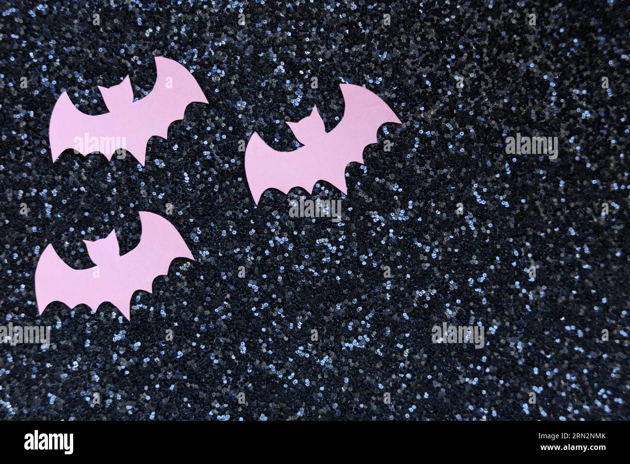 Pinkfarbene Fledermäuse auf schwarzem Glitzerhintergrund halloween-Konzept Stockfoto