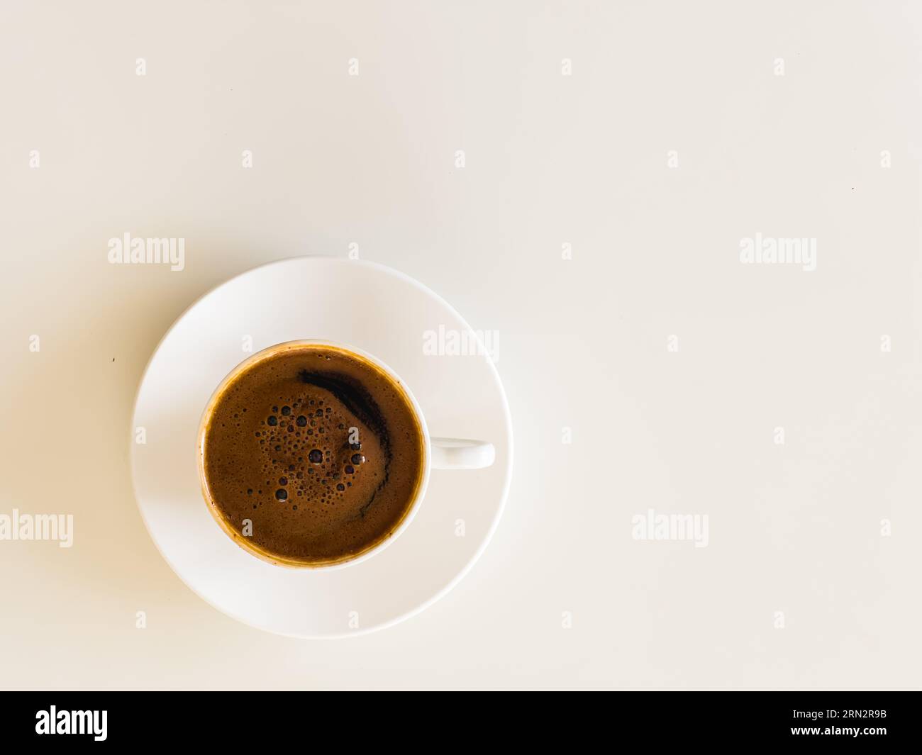 Kleine weiße Porzellantasse und Untertasse mit heißem, schwarz gebrühtem türkischem Kaffee, Kaffeekultur-Konzept. Isoliert auf weiß. Blick von oben. Hochwertige Fotos Stockfoto