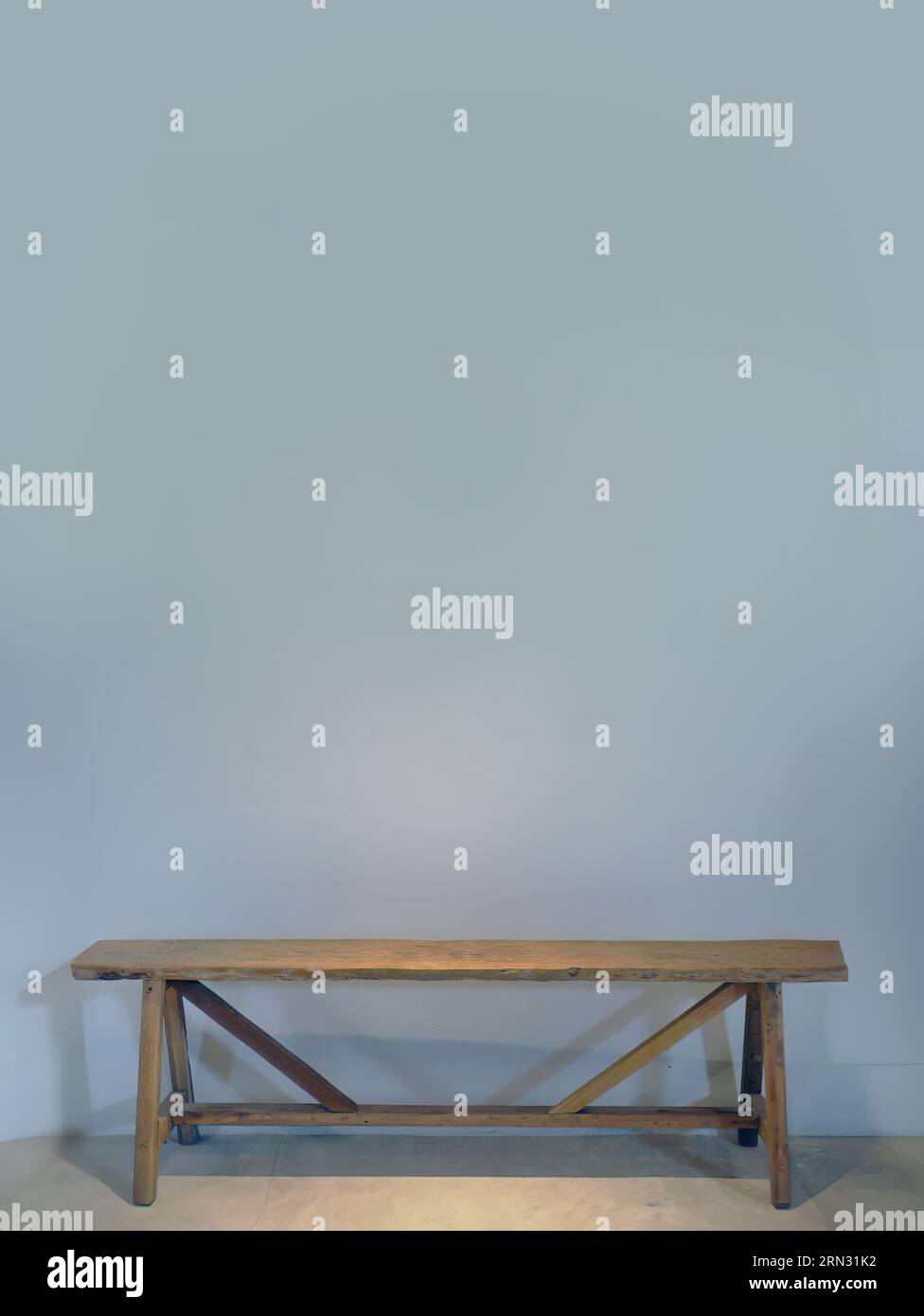 Eine leere blaue graue Farbwand mit einer Holzbank an der Wand, gepunktete Beleuchtung von oben, leerer Platz für Kopien oder Texteinfügungen, Grafikressourcen Stockfoto