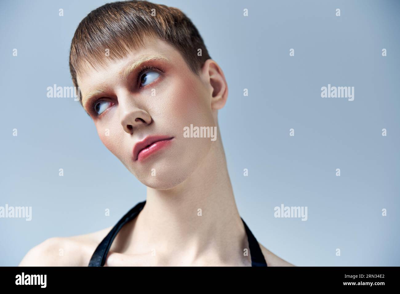 Porträt, androgynes Modell mit Make-up auf grauem Hintergrund, Schönheit und Aussehen, queer Stockfoto