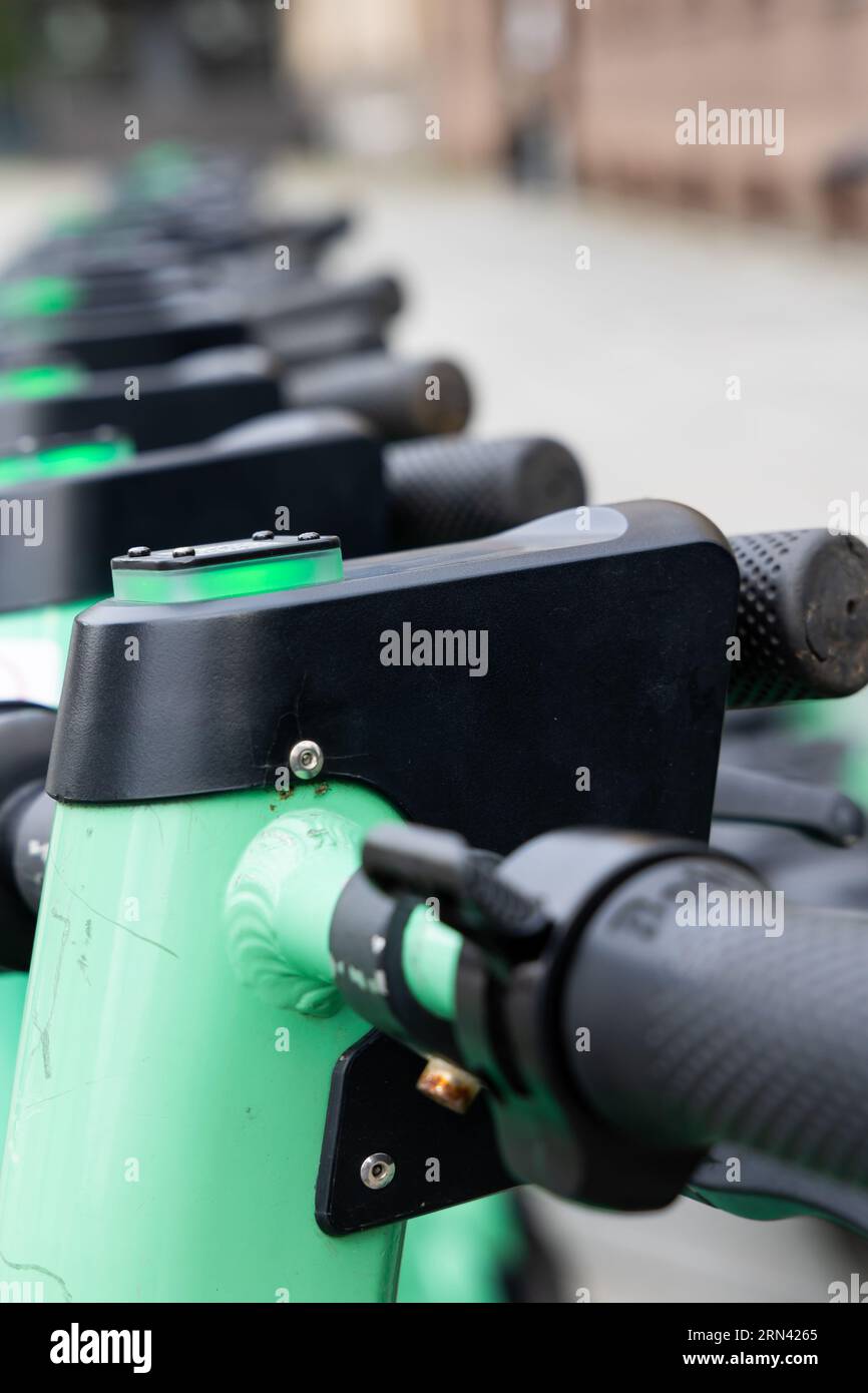 Nahaufnahme des Lenkers eines grünen Elektrorollers. Verschwommene Stadt im Hintergrund. Privatfahrzeuge für den Stadtverkehr können gemietet werden Stockfoto
